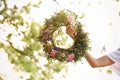 Young woman holding wreath made of beautiful flowers outdoors on sunny day, closeup Royalty Free Stock Photo