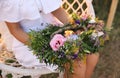 Young woman holding wreath made of flowers on swing chair outdoors at sunset, closeup Royalty Free Stock Photo