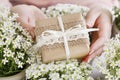 Young woman holds, a beautifully wrapped, gift. Flowers around her Royalty Free Stock Photo