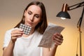 Young woman holds a blister pack of pills and reads medical instructions Royalty Free Stock Photo