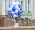 A young woman holds a bunch of colorful balloons in her hands