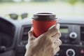 Young woman holds disposable cup of coffee in the car, to keep concentrated while driving. Royalty Free Stock Photo