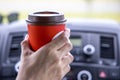 Young woman holds disposable cup of coffee in the car, to keep concentrated while driving. Royalty Free Stock Photo