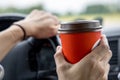 Young woman holds disposable cup of coffee in the car, to keep concentrated while driving Royalty Free Stock Photo