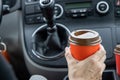 Young woman holds disposable cup of coffee in the car, to keep concentrated while driving. Royalty Free Stock Photo