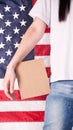 Young woman holds empty cardboard with Space for Text sign against American flag on background. Girl protesting anti-abortion laws