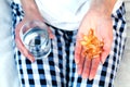 Young woman holds a a handful capsules of Omega-3 fatty acid and glass of water in hands. Taking vitamins, supplements.