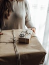 Young woman holds in hands stacked Christmas gift boxes in craft paper with juniper. Christmas presents concept Royalty Free Stock Photo