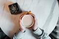 Young woman holds in her hands a cup with a hot sweet cappuccino sitting at a table in a cafe. Great morning for coffee gourmets. Royalty Free Stock Photo