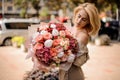 Young woman holds bouquet of peonies, hydrangea, roses and red berries.