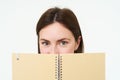 Young woman holds notebook daily planner next to her face, writing down homework, making notes, looking thoughtful Royalty Free Stock Photo