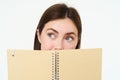 Young woman holds notebook daily planner next to her face, writing down homework, making notes, looking thoughtful Royalty Free Stock Photo