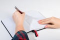 Young woman holds a pen in her left hand and writes note in blank notebook. International Left-Handers Day