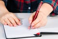 Young woman holds a pen in her left hand and writes note in blank notebook. International Left-Handers Day