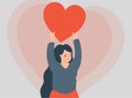 Young woman holds a red heart above her head. Happy teenage female lifts up a big heart isolated. valentine\'s day concept Royalty Free Stock Photo