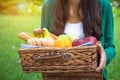 Young woman holds straw basket with healthy food, bananas, apple, orange, corn, whole wheat bread vegetables and fruits Royalty Free Stock Photo