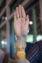 young woman holds up her hand wearing gold heart-shaped bracelet and pendant to greet and symbolizes love and friendship with