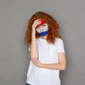 Young woman with Holland flag painted on her face