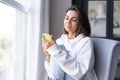 A young woman at home in a cozy white hoodie