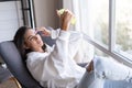 A young woman at home in a cozy white hoodie