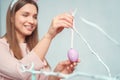 Young woman at home easter celbration concept decorating tree with egg