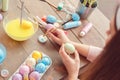 Young woman at home easter celbration concept back view sitting coloring eggs dipping brush in paint