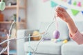 Young woman at home easter celebration concept hanging egg on tree