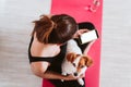 Young woman at home relaxed using mobile home. sitting on a yoga mat with her cute small dog besides. Technology and healthy lifes Royalty Free Stock Photo