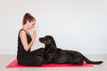Young woman at home relaxed using mobile home. sitting on a yoga mat with her black labrador dog besides. Technology and healthy Royalty Free Stock Photo