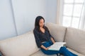 A young woman at home sitting on the couch by the window relaxing in her living room reading a book Royalty Free Stock Photo