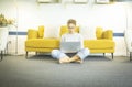 Young woman at home sitting on floor with crossed legs working or studying using laptop in the living room at home. Woman sitting Royalty Free Stock Photo