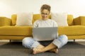 Young woman at home sitting on floor with crossed legs working using laptop in the living room at home. Woman sitting on living Royalty Free Stock Photo