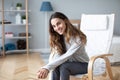 Young woman at home sitting on modern chair relaxing in her living room Royalty Free Stock Photo