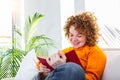 Young woman at home sitting on modern sofa relaxing in her living room reading book . White cozy bed and a beautiful girl, reading Royalty Free Stock Photo