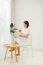 Young woman at home sitting near window relaxing in her living room reading book and drinking tea Royalty Free Stock Photo