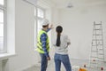 Young woman homeowner discussing design project of her new apartment with a foreman standing back. Royalty Free Stock Photo