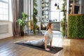 Young woman in homeware practicing balance yoga pose on carpet in her comfy bedroom.