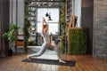 Young woman in homeware practicing balance yoga pose on carpet in her comfy bedroom.