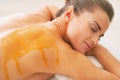 Young woman with honey on back laying on massage table Royalty Free Stock Photo