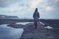 Young woman in hooded coat walking on beach Royalty Free Stock Photo