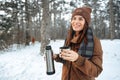 Young woman with hot drink thermos at winter forest Royalty Free Stock Photo