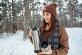 Young woman with hot drink thermos at winter forest Royalty Free Stock Photo