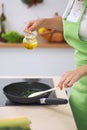 Young woman housewife cooking in the kitchen while adding olive oil. Concept of fresh and healthy meal at home Royalty Free Stock Photo