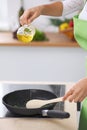 Young woman housewife cooking in the kitchen while adding olive oil. Concept of fresh and healthy meal at home Royalty Free Stock Photo