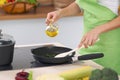 Young woman housewife cooking in the kitchen while adding olive oil. Concept of fresh and healthy meal at home Royalty Free Stock Photo