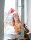 Young woman housewife washes a window