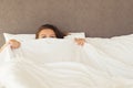 A young woman with huge frightened open eyes lying in bed and covers herself with the sheets and hides. Nightmares, insomnia, phob Royalty Free Stock Photo