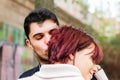 Young woman hugging her boyfriend while he gives her an affectionate kiss on the face. Concept of couple, tenderness and Royalty Free Stock Photo