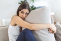 Young woman hugging pillow with depression and crying on sofa at home. Lonely millennial lady feeling stressed and hopeless, Royalty Free Stock Photo