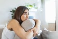 Young woman hugging pillow with depression and crying on sofa at home. Lonely millennial lady feeling stressed and hopeless, Royalty Free Stock Photo